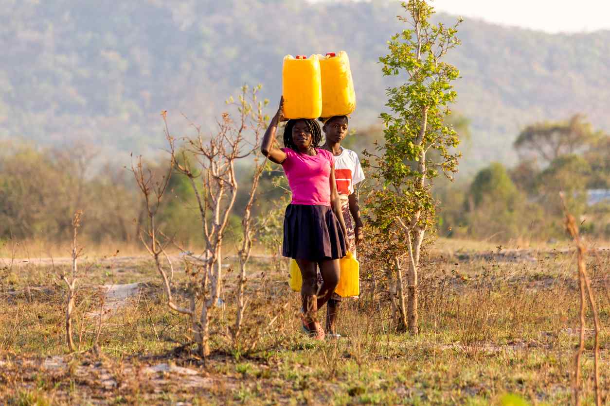 Due ragazze che trasportano litri d'acqua sulla testa in una regione con scarsità d'acqua